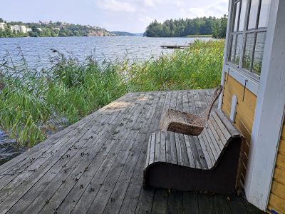 En brygga med en träbänk och en korgstol med utsikt över vattnet