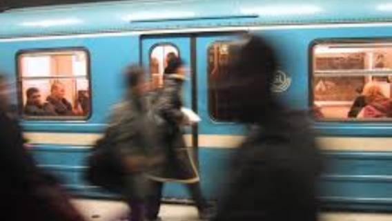 blå tunnelbanevagn med anonyma resenärer som hastar förbi på perrongen
