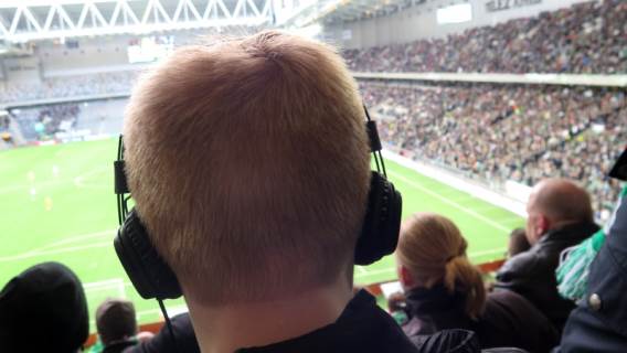Bild från Tele 2 Arenas läktare med huvud med hörlurar i förgrunden.