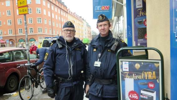 Två poliser intill godkänd skylt på en trottoar.